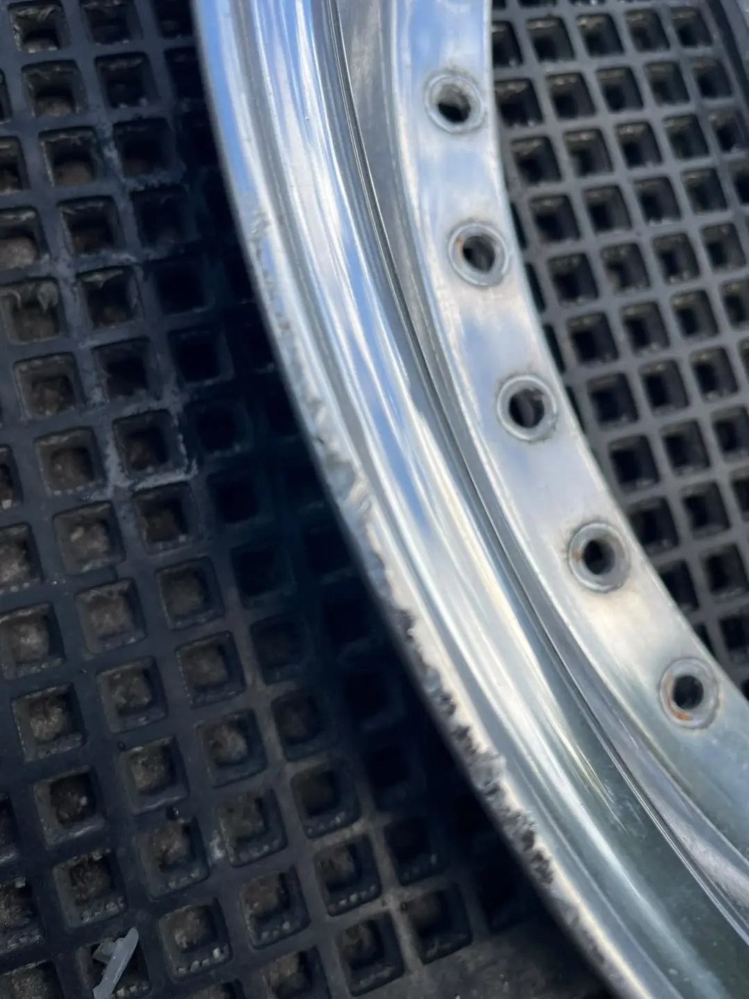 A split-rim barrel lip before restoration, with pitted, dull polish and corrosion around the rivet holes