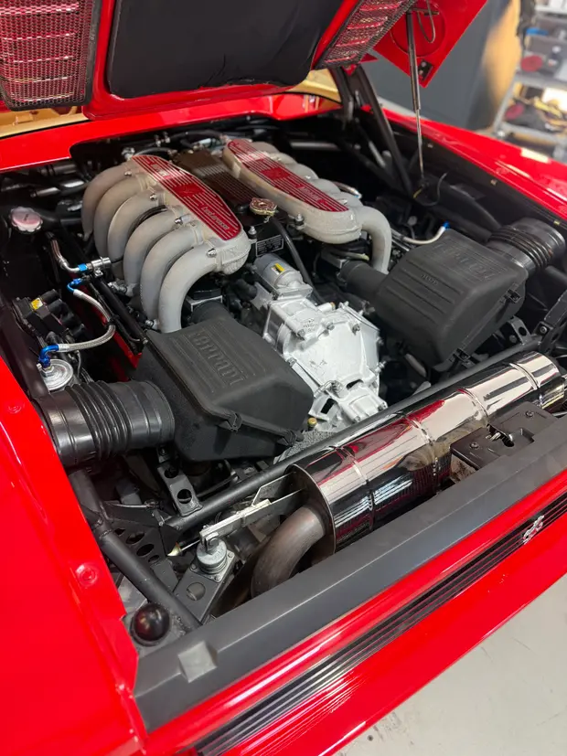 The engine bay of a red sports car, opened for work