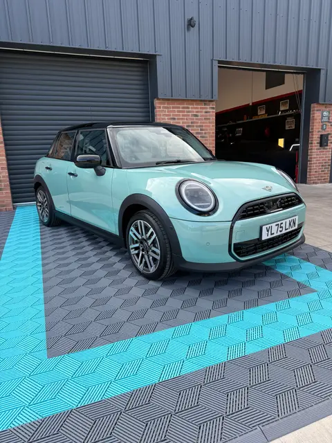 A pale green small hatchback photographed outside the workshop