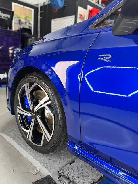 A blue hatchback on the ramp in the ALC Elite workshop, with an interior view