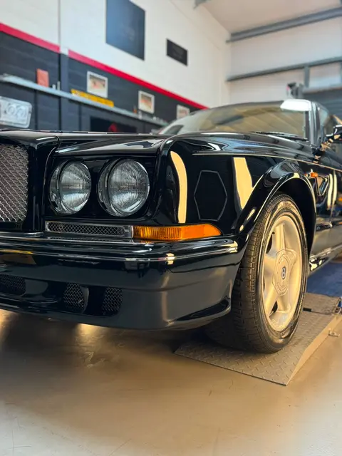 A black coupé on the ramp in the ALC Elite workshop, with wheel and interior details